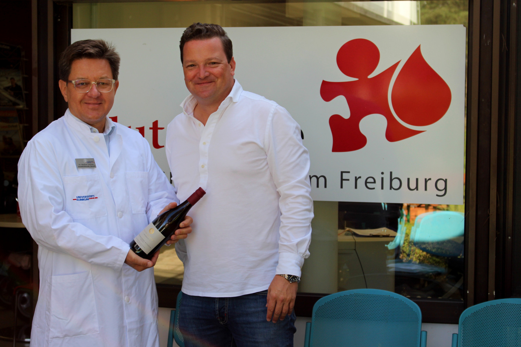 Dr. Markus Umhau,  Ärztlicher Leiter der Blutspendezentrale am Universitätsklinikum Freiburg (links im Bild), nimmt die Weinspende des Badischen Weinbauverbandes von dessen Geschäftsführer Holger Klein entgegen.