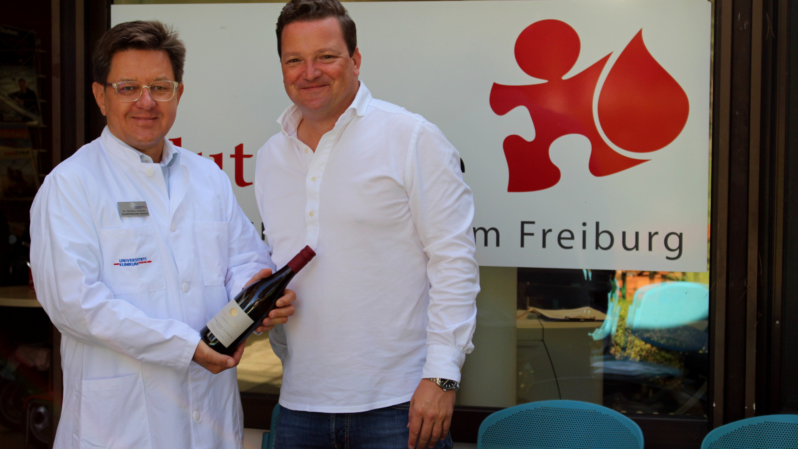Dr. Markus Umhau,  Ärztlicher Leiter der Blutspendezentrale am Universitätsklinikum Freiburg (links im Bild), nimmt die Weinspende des Badischen Weinbauverbandes von dessen Geschäftsführer Holger Klein entgegen.